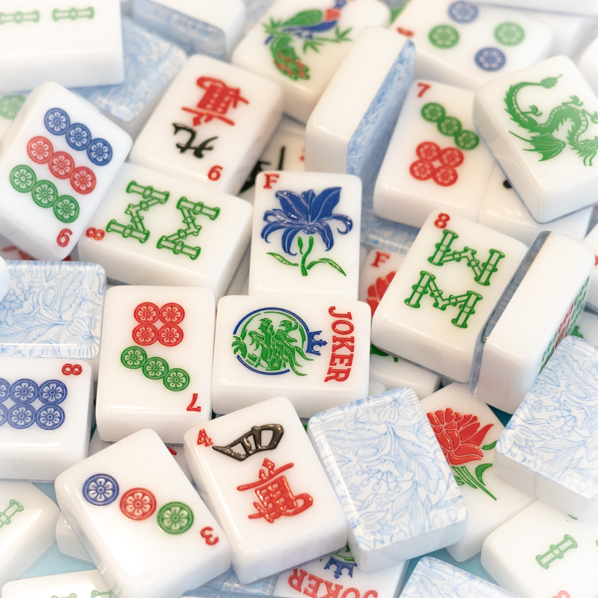 An image of a jumble of tiles from the Modern Classic tile line from Mahj Queen™. It highlights the classic colors of the tiles, beautiful top layer design and unique tile artwork.