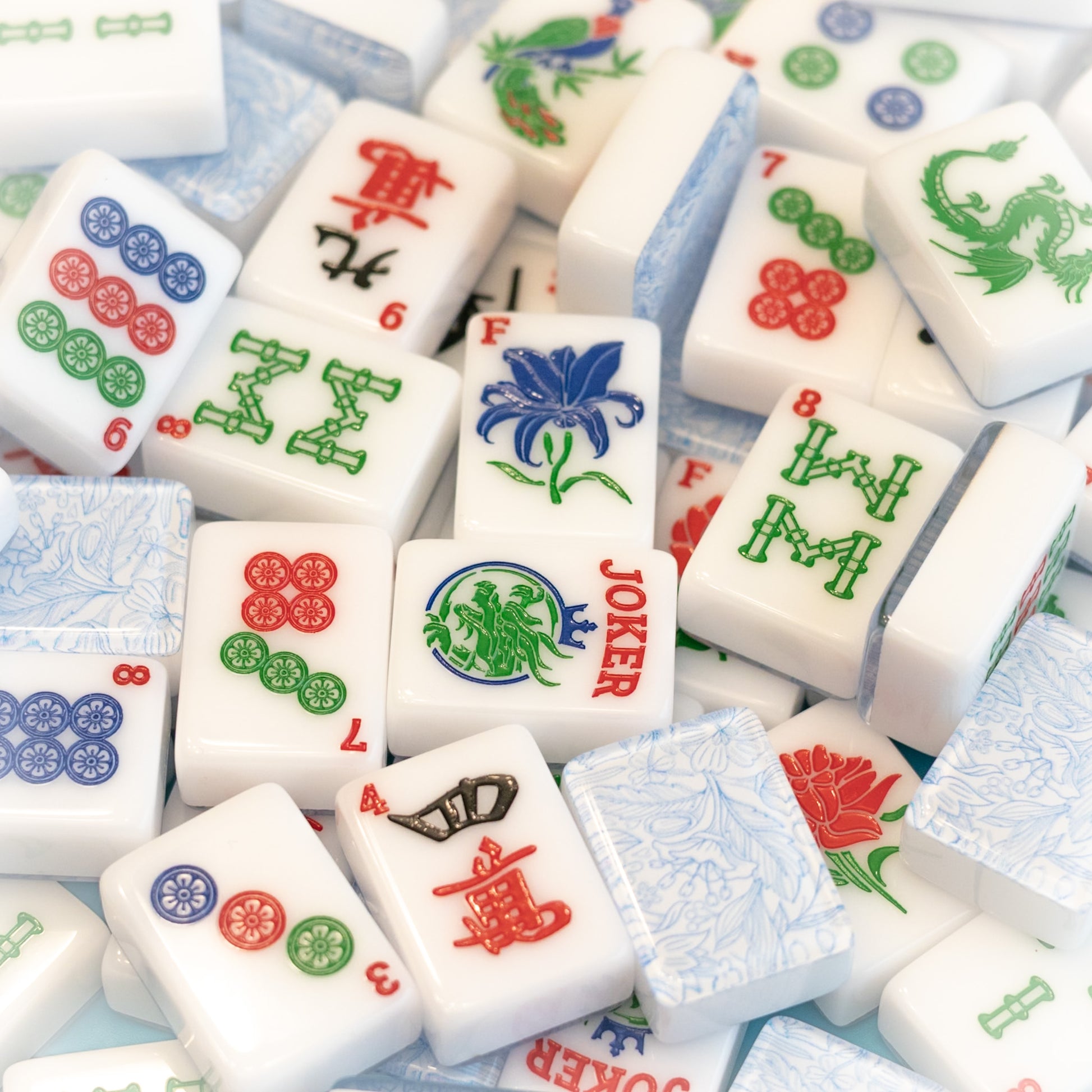 An image of a jumble of tiles from the Modern Classic tile line from Mahj Queen™.  It highlights the classic colors of the tiles, beautiful top layer design and unique tile artwork.